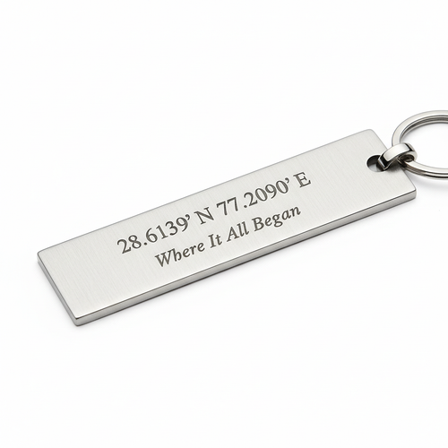 Slim rectangular silver metal keychain engraved with GPS coordinates and Where It All Began text in fine elegant font on white background