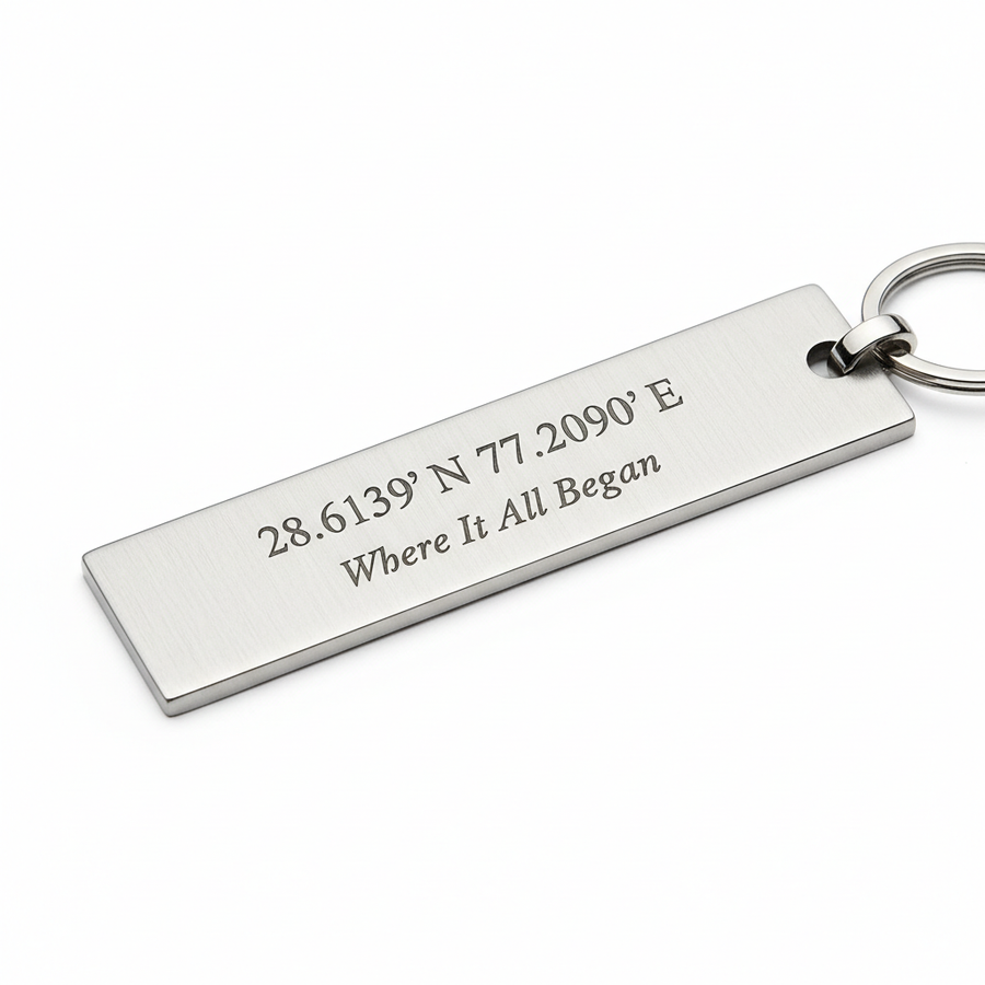 Slim rectangular silver metal keychain engraved with GPS coordinates and Where It All Began text in fine elegant font on white background